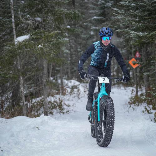 A man on his fat bike in the wintery woods