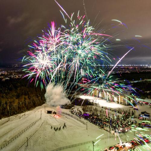 A bright firework show going off over a snowy hill