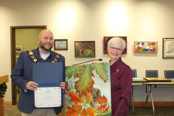 Artist and mayor standing together holding fall painting