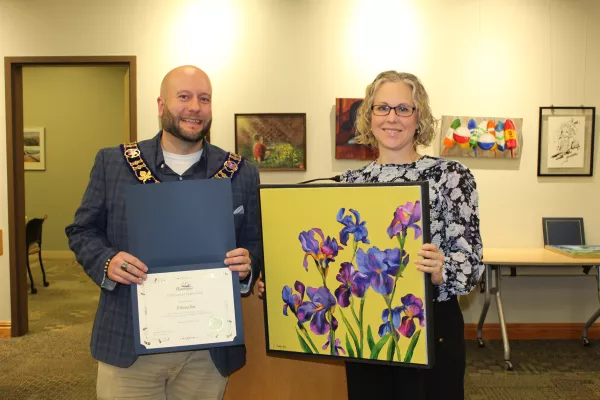 Artist holding yellow painting with purple flowers with mayor