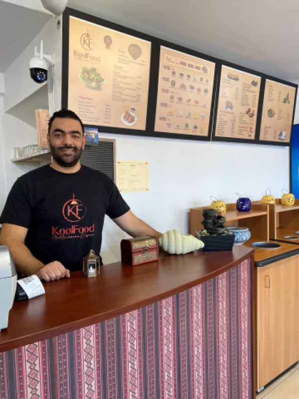 Restaurant owner standing behind counter smiling