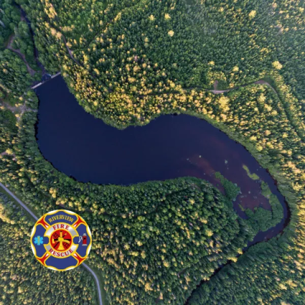 Aerial view of lake surrounded by trees with fire & rescue logo 