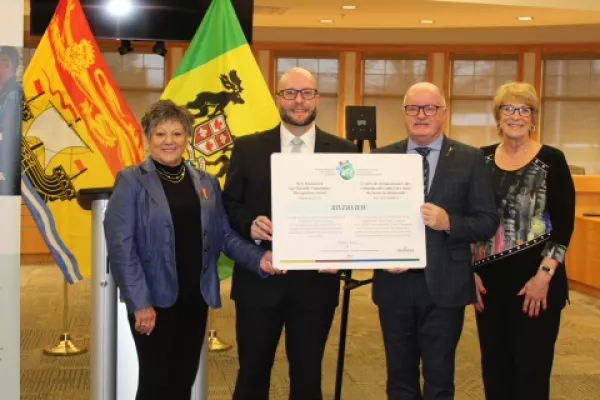 Council members standing in council chambers with plaque