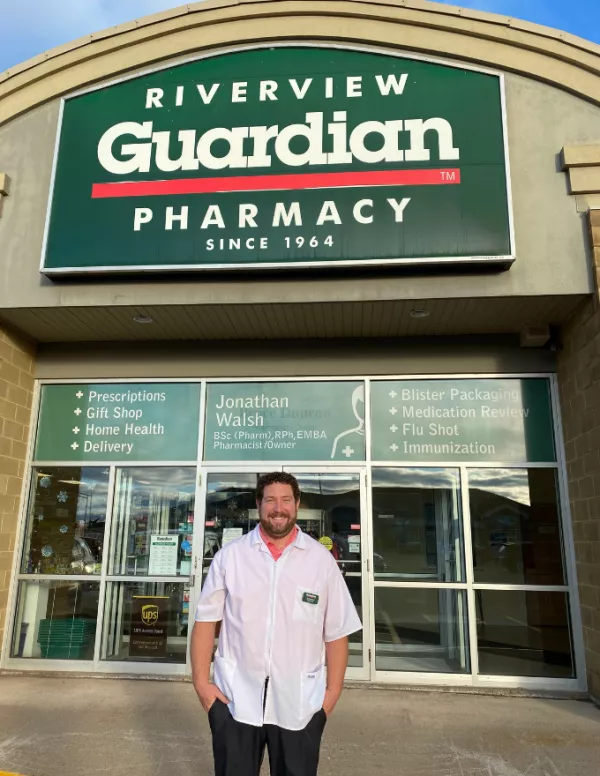 Man standing in front of green pharmacy sign