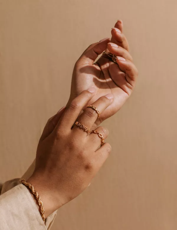 A woman's hands adorned with rose gold rings and bracelets 