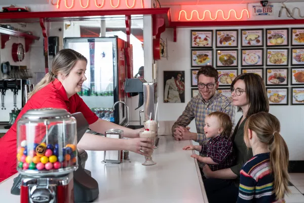A waitress serving a family milkshakes 