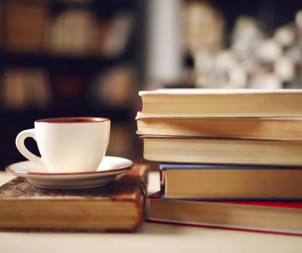 A pile of books and a small cup of coffee