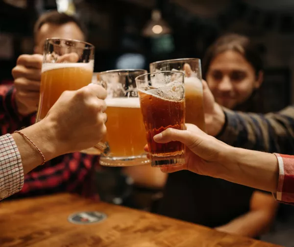 A group of people lifting their glasses of beer together 