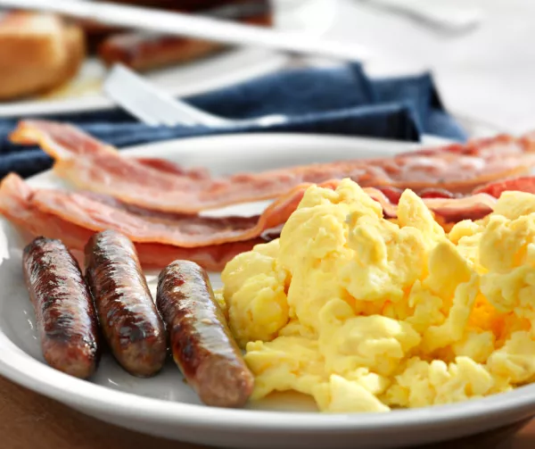 Scrambled eggs, bacon, and sausage on a plate 