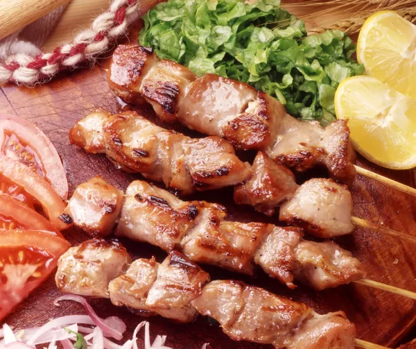 Meat kebabs and various toppings on a cutting board 