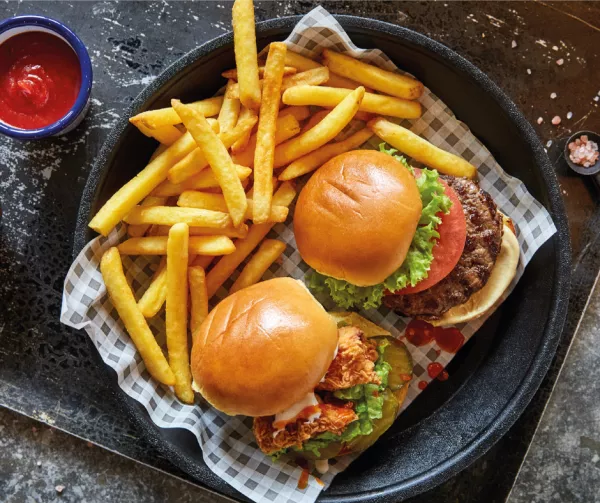 A beef burger and a chicken burger on a platter with fries