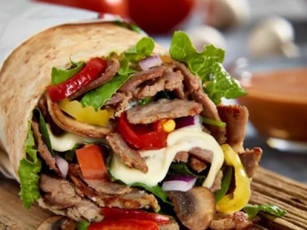 A pita filled with steak and vegetables 