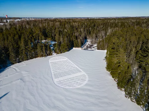 A snowshoe design imprinted on the snow covering a frozen lake