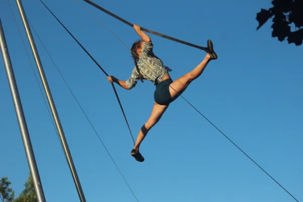 A woman suspended in the air doing acrobatics outside