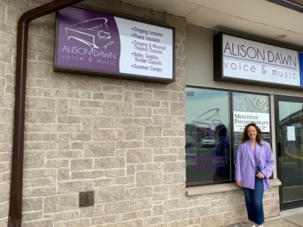 Owner of Alison Dawn voice and music standing and smiling outside storefront