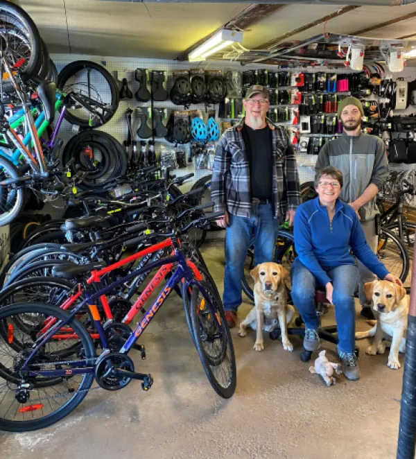 3 people and 2 golden labs standing inside a bike shop