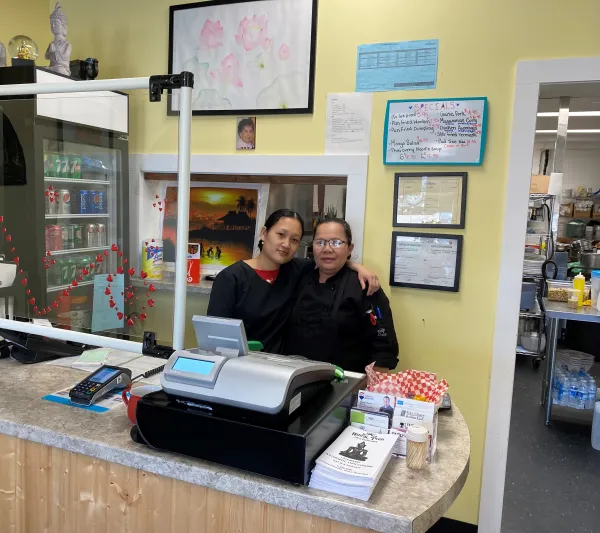 Owner and staff member of Royal Thai Restaurant smiling at front counter