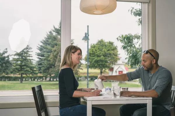 A couple at a restaurant table by a window drinking tea