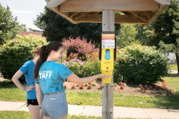 Two people using outdoor sunscreen dispenser