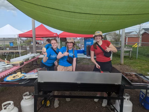 Three students running a BBQ in the community garden