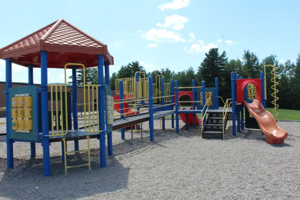 A playpark located by Claude D. Taylor School with trees and blue cloudy sky in the background