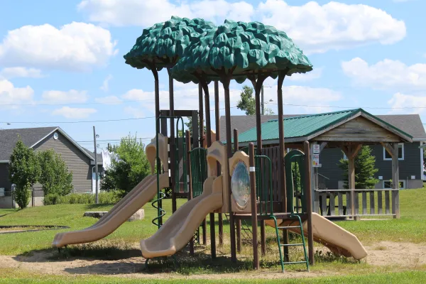 A playground with blue cloudy sky in the background located on Rebecca Avenue. 