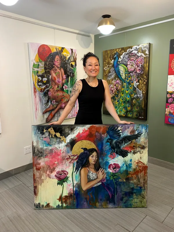 Artist standing inside her studio with her paintings