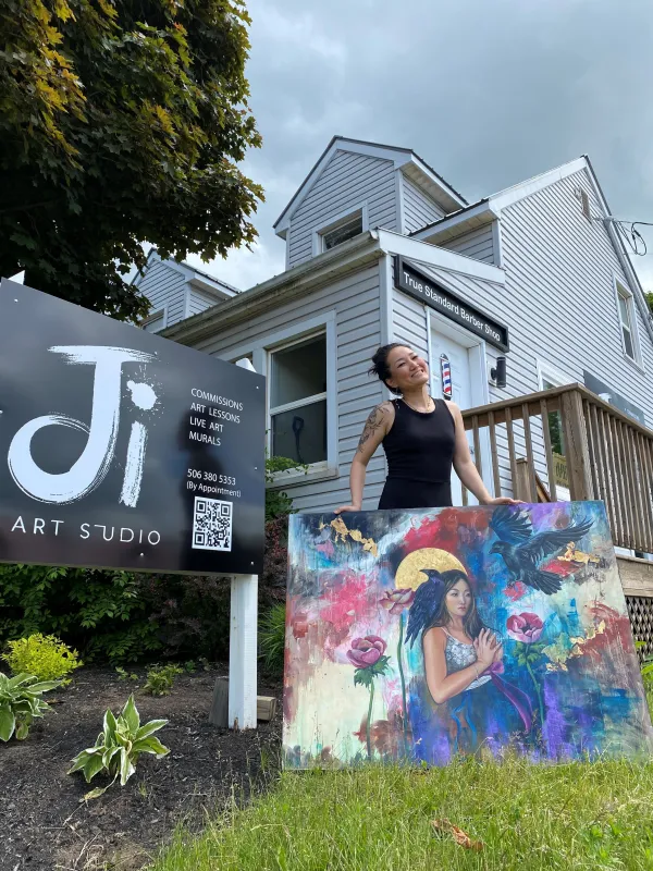 Artist standing outside her studio with her paintings