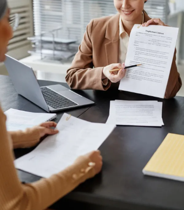 2 People in a meeting room reviewing documents.