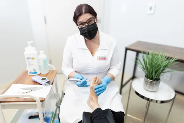 Footcare specialist holding a foot and a medical tool.