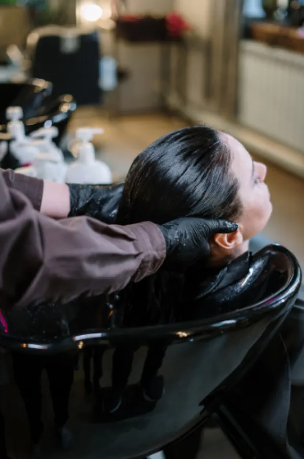 Stylist washing a clients hair at the shampoo bowl