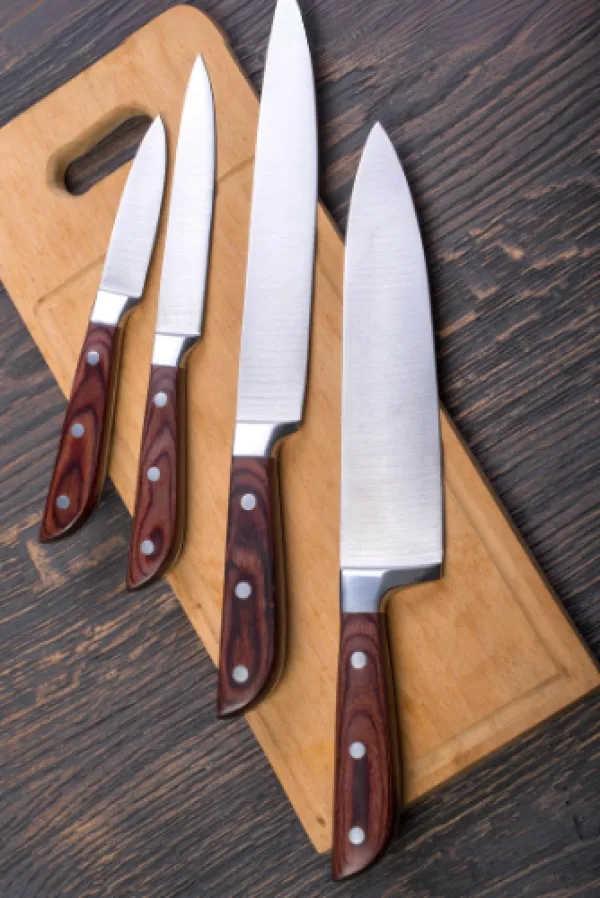 Wooden handled stainless steel knifes on a cutting board.