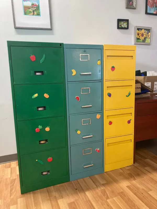 3 brightly coloured filing cabinets (green, blue, and yellow) with fruit and vegetable magnets