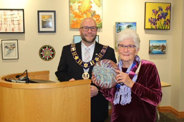 Artist smiling holding artwork with mayor