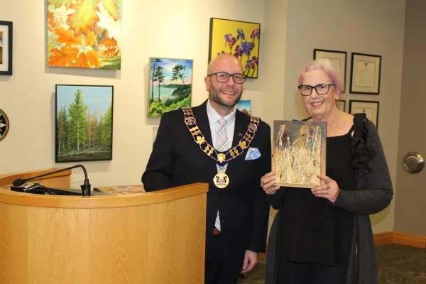 Artist holding artwork with mayor, smiling