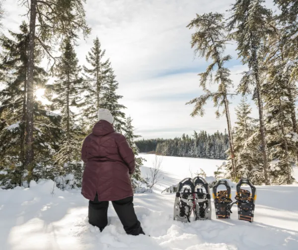 A woman looking over a snowy landscape with snowshoes