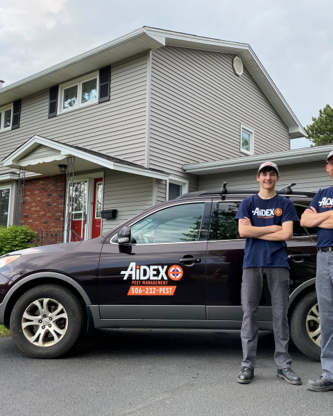 Dale Hatchard of Aidex Pest Management standing outside his branded vehicle with his son