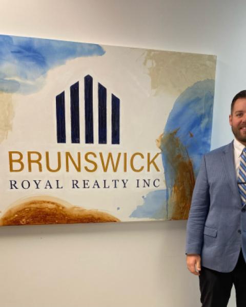 Realtor standing by office sign