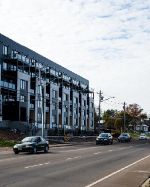 A new apartment building with a "now leasing" sign out front