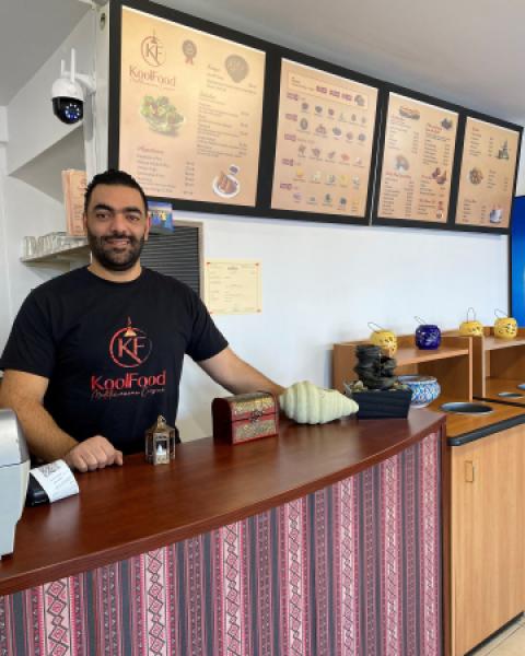 Restaurant owner standing behind counter smiling