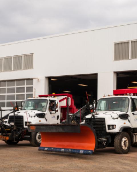 Two snowplows pulling out of garage