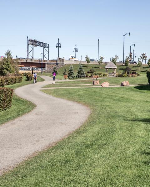 a tidy walking path next to the river with two bikers on it