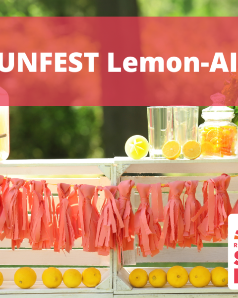 photo of a lemonade stand with a red banner overtop that reads "SUNFEST Lemon-AID" with the Riverview Sunfest logo on the bottom right of the image