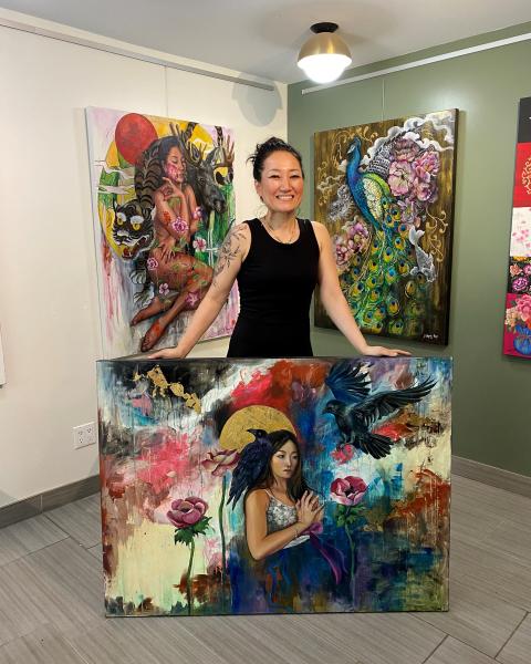 Artist standing inside her studio with her paintings