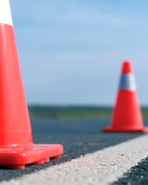 Two orange pylons set along a solid white line on the road