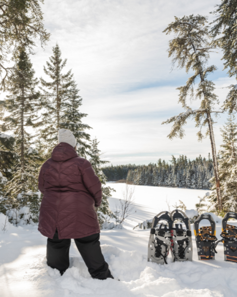 A woman looking over a snowy landscape with snowshoes