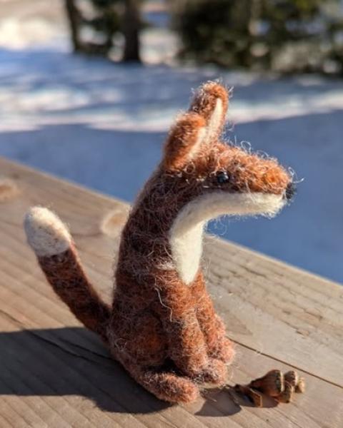 Stuffed felt fox sitting on an outside deck